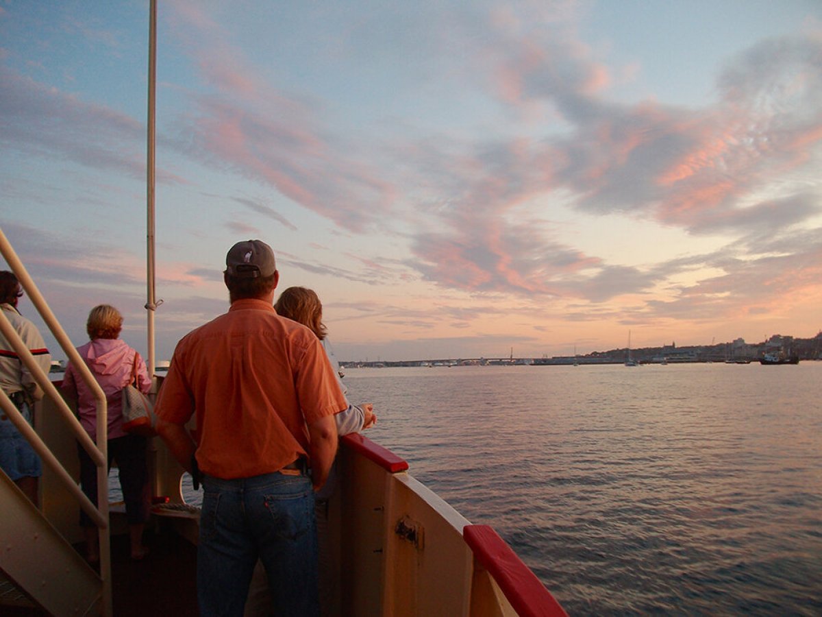 a man standing in front of a boat next to a body of water
