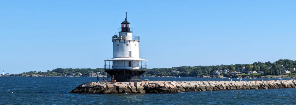 Lighthouse on a rocky pier under a clear blue sky