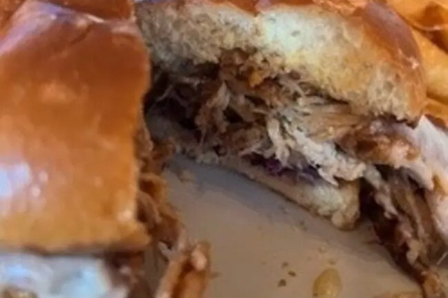 Close-up of a pulled pork sandwich on a bun.